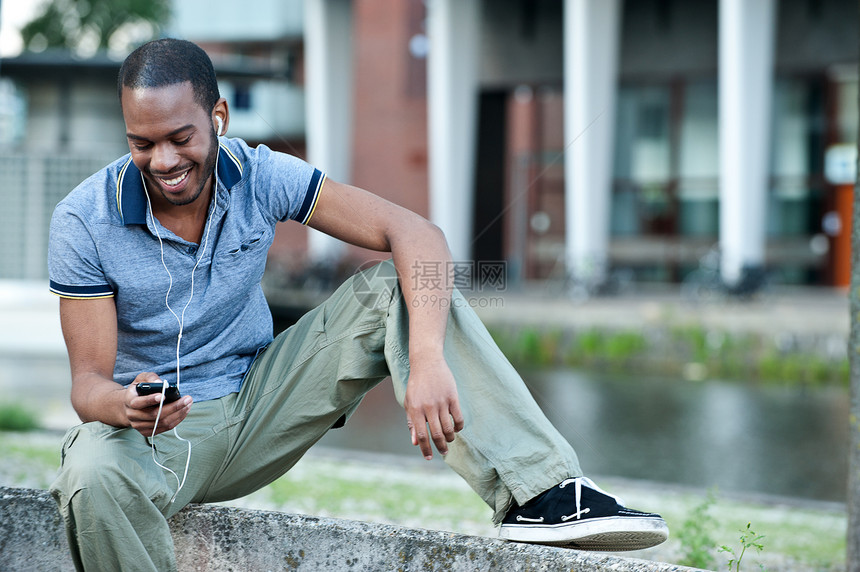 一名年轻黑人男性在外边听耳语音乐的无纸图像图片
