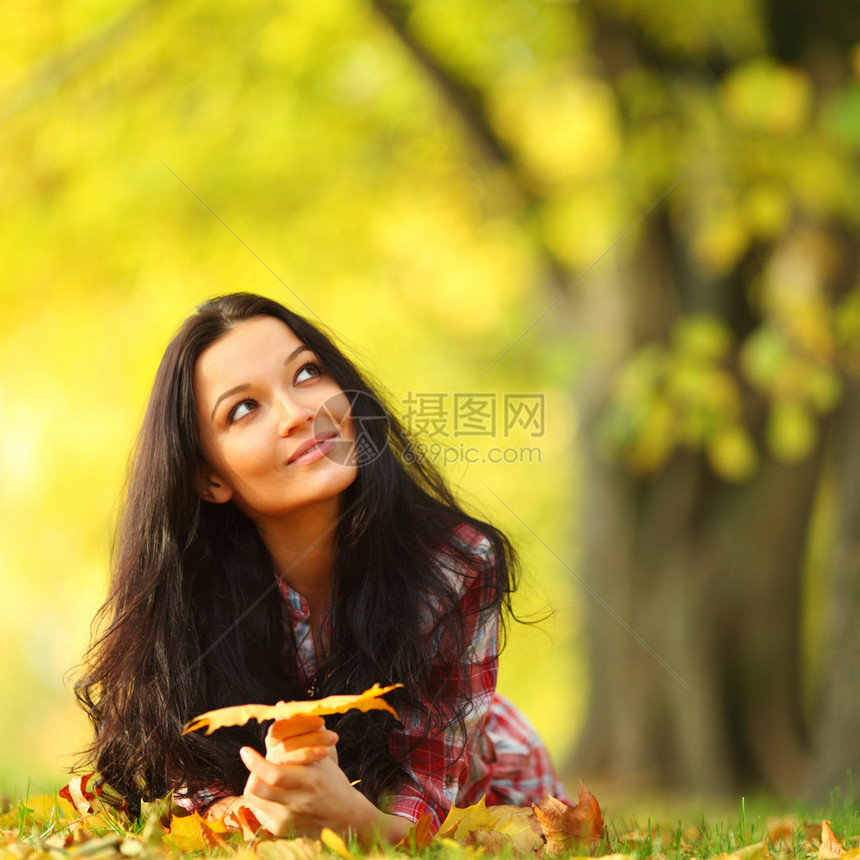 秋叶中的妇女脚尖女士微笑女性金发女郎公园头发幸福季节成人叶子图片