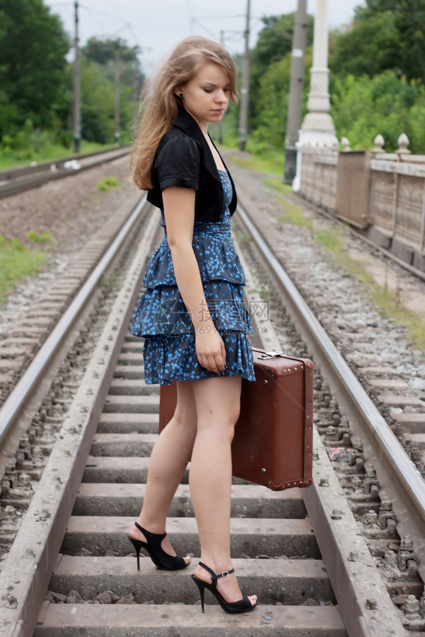 女孩拿着手提箱站在铁轨上旅行假期女士蓝色头发铁路裙子运输冒充火车图片