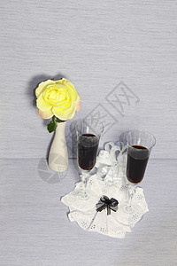 两杯葡萄酒和一朵黄玫瑰花瓶鞋带灰色红色黄色玫瑰白色纳金绿色背景图片