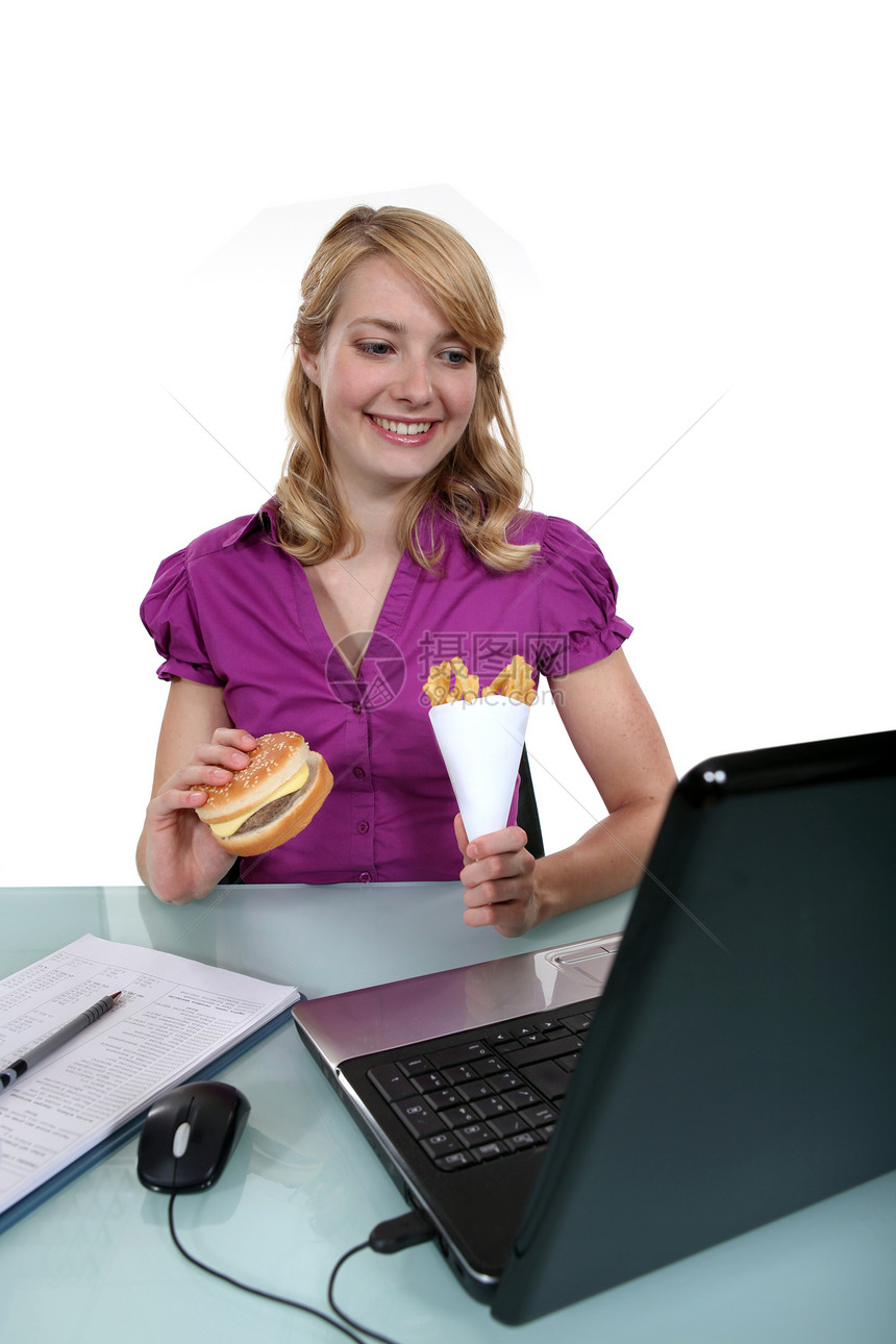 一个在办公室吃垃圾食品的女商务人士图片
