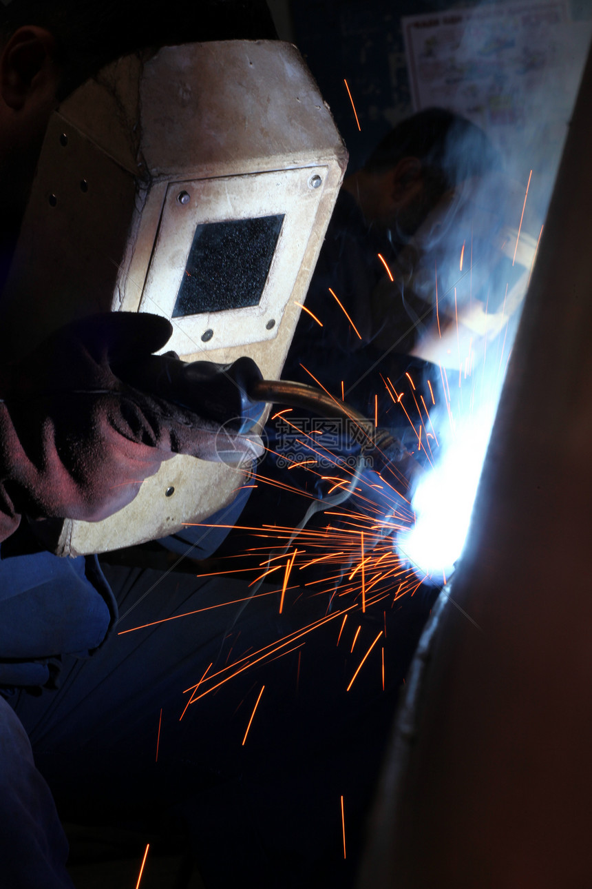 工厂内戴保护面罩的焊接机劳动者工作乙炔维修工具劳动工人生产火焰火花图片