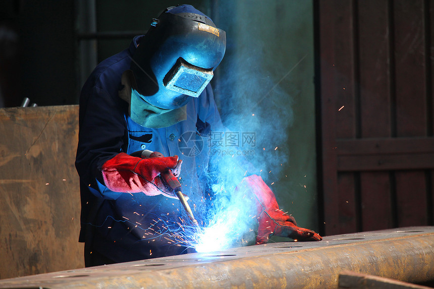 工厂内戴保护面罩的焊接机焊机火花男性工匠生产工人头盔面具大厅蓝色图片
