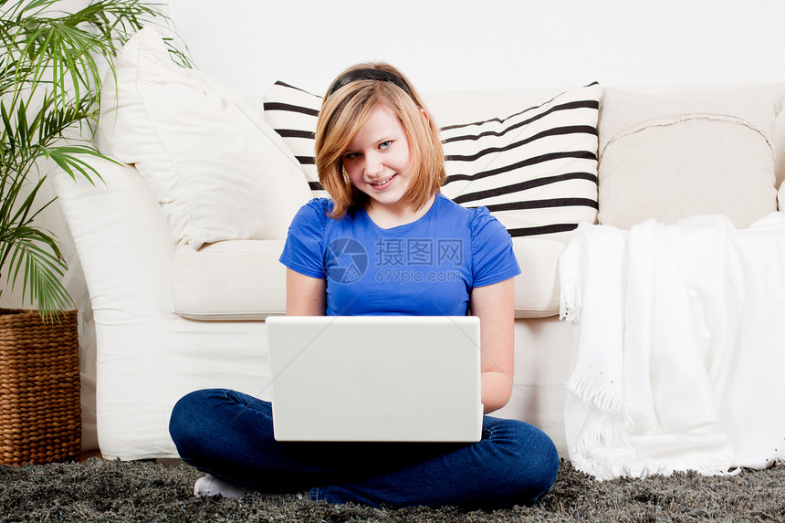 拥有笔记本电脑的年轻少女房间休息长椅乐趣微笑图书幸福女学生互联网说谎图片
