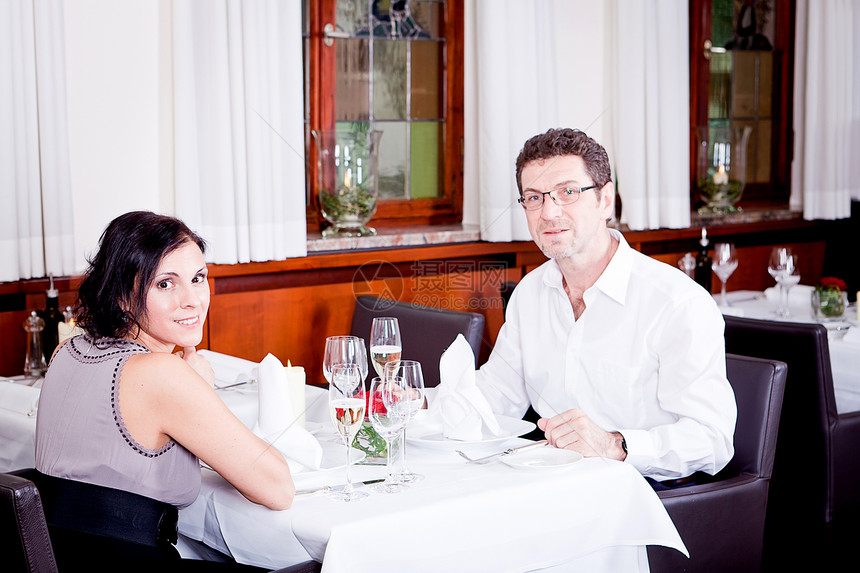快乐的一对在餐厅笑着微笑的情侣生日幸福浪漫庆典推介会成人女士用餐玻璃纪念日图片
