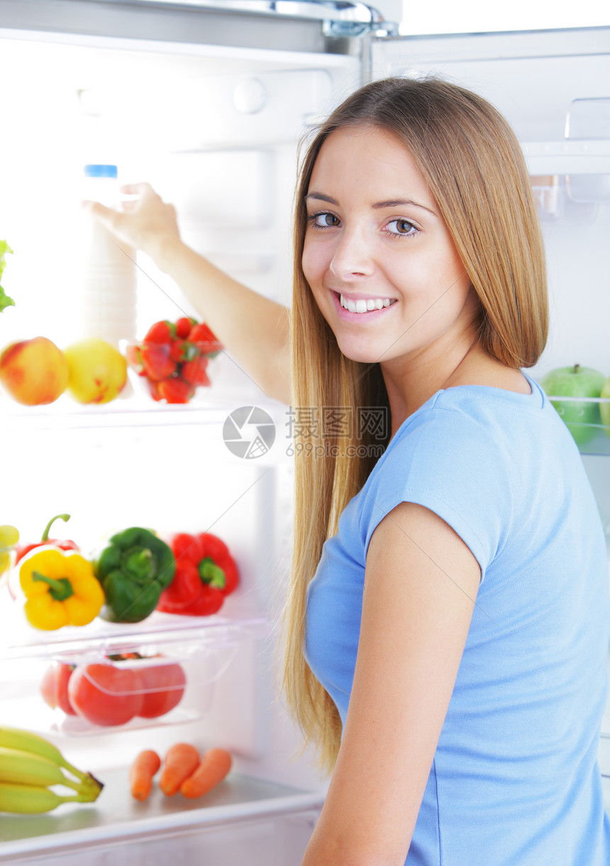 冰箱中的牛奶饮食微笑金发女郎蔬菜瓶子蓝衬衫水果厨房表达生活图片