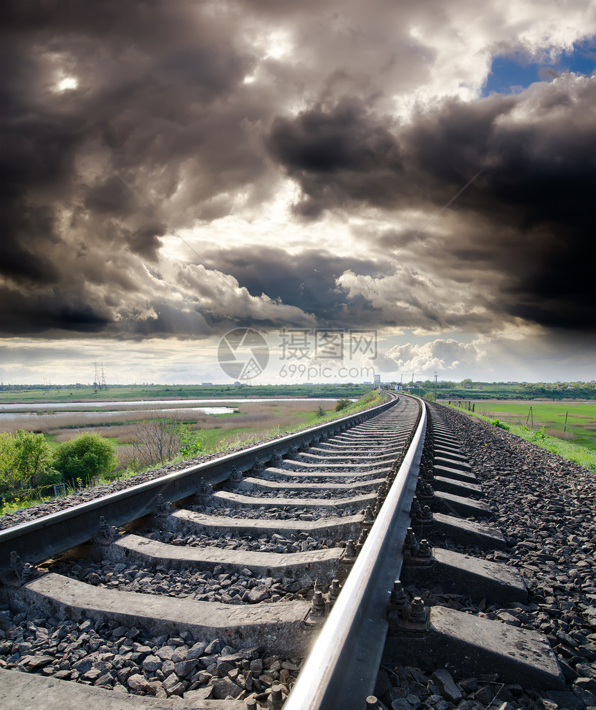 铁道在阴云的天空下与太阳相望图片