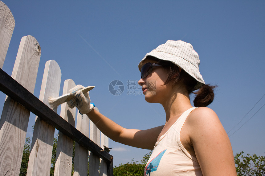 美丽的女孩在木栅栏上涂着美丽女孩的颜色住宅装修栏杆女士装潢平反房子勤勉白色画家图片