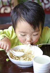 婴儿面条可爱的宝宝在吃东西面条后代肩膀托盘摄影孩子童年男生食物背景