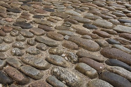 在欧洲一条街道上铺筑路障的格局椭圆形石头材料说谎城市对角线背景图片