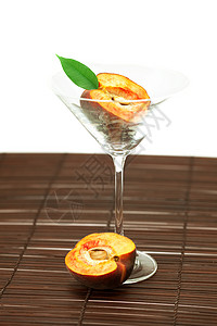 玛蒂尼酒杯中的桃子 在竹垫上黄色圆圈阴影水果橙子材料玻璃条纹曲线红色黄色的高清图片素材
