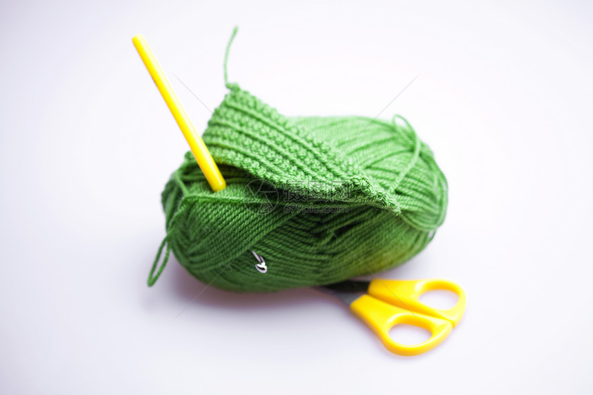 在灰色的背沟上用剪刀和编织钩来磨羊毛白色艺术羊绒幽默物品绿色风格细绳工艺针织图片