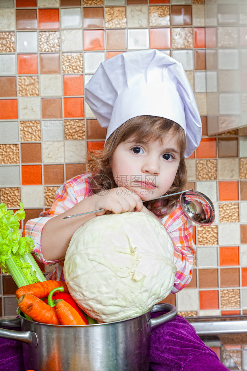 配蔬菜的婴儿厨师坐在厨房桌上生长帽子女孩孩子童年孩子们沙拉平底锅饮食烹饪图片