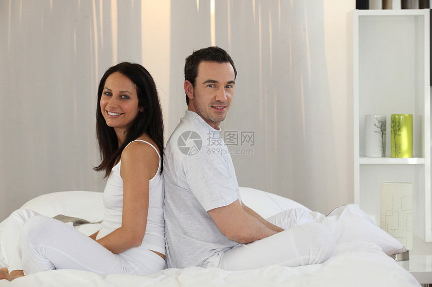 坐在床上的一对夫妇压痛时间女朋友枕头女士拥抱男人男朋友女性眼睛图片