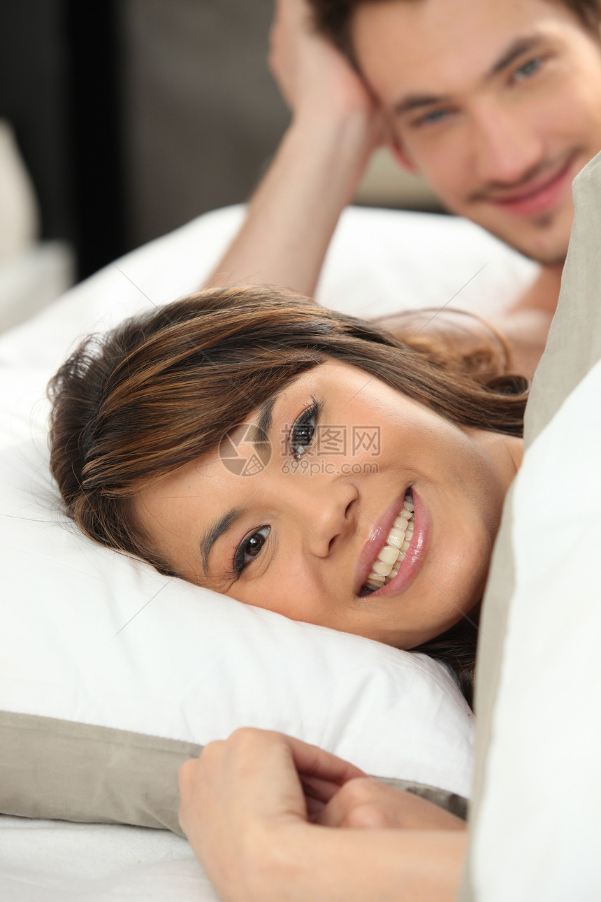 快乐的年轻夫妇躺在床上图片