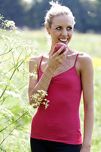 田里吃苹果的女人场地快乐水果晴天女士女性微笑草地背景图片
