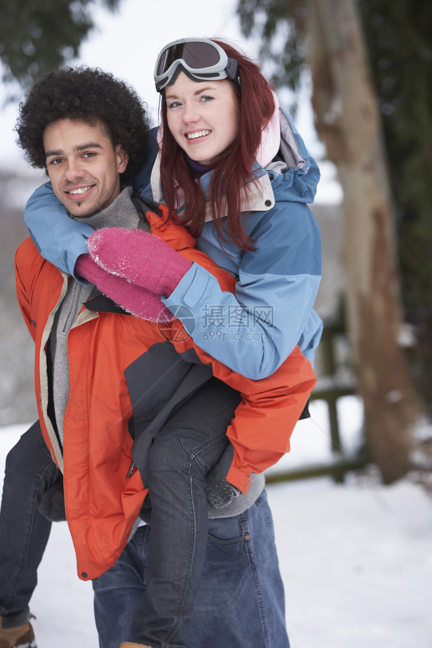 在雪地风景中骑着小男孩给女孩搭便车季节笑声围巾寒冷下雪男人天气两个人亲热女性图片