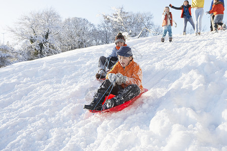 雪孩子素材带着家庭守望的年轻男孩滑雪下山四个人母亲男性场景场地父亲雪橇女孩女性女士背景