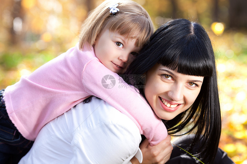 美丽的年轻母亲背着女儿抱着她的女儿图片