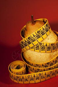 带有测量胶带的梨子贪食症磁带水果厌食症重量食欲概念红色饮食背景图片