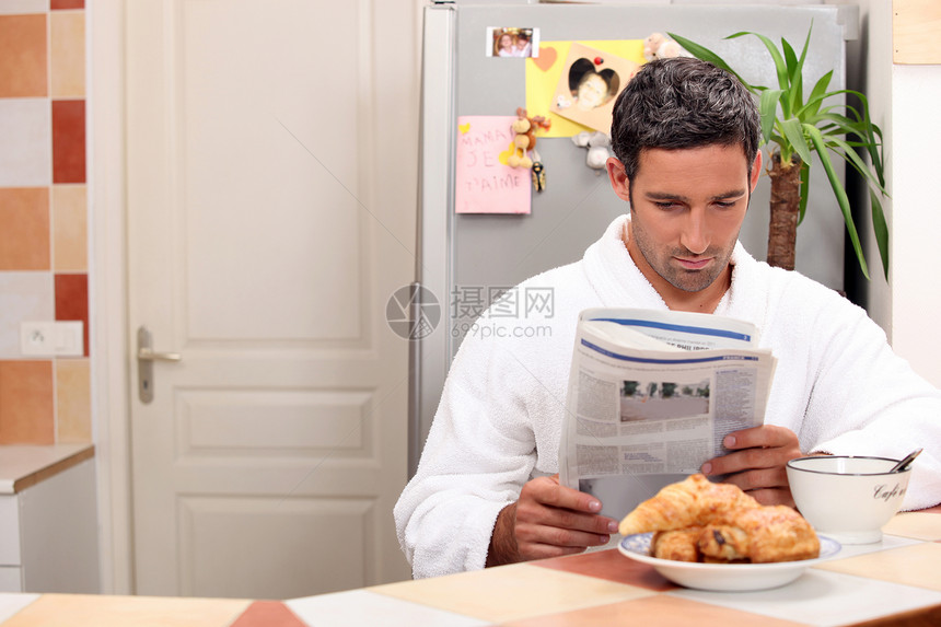 男人在吃早餐时看报纸图片