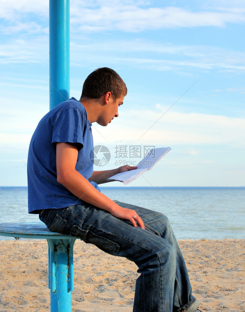 青少年在户外阅读信件日落阅读文学孤独男性支撑天空座位海岸牛仔裤图片