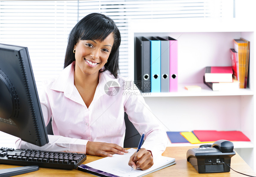 在办公桌上微笑的黑人女商务人士软垫就业办公室记事本工人员工商务商业女性笔记图片