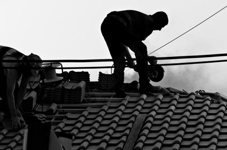 在屋顶上辛劳劳动的工业工人建造高清图片素材