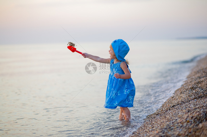 海滩上的小女孩女性海岸童年日落海浪衣服乐趣孩子场景卵石图片