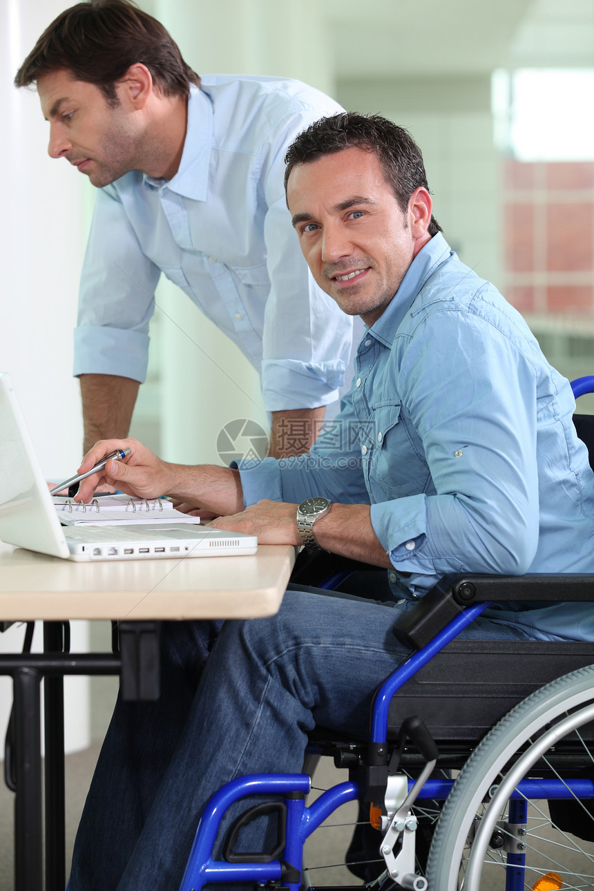 坐在轮椅上的男人老板电脑蓝色合作衬衫多样性助手黑发窗户技术图片