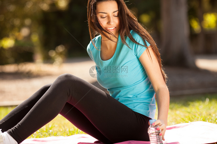 年轻美丽的运动女青年即将喝水了瓶子女孩运动员公园森林微笑赛跑者训练女性蓝色图片
