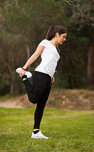 年轻美丽的女士拉伸音乐绿色公园女孩重量肌肉头发健身房耳机拉丁背景图片