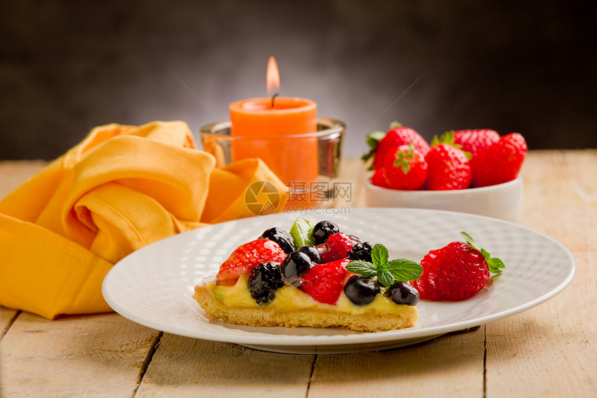 用蜡烛和草莓饼奇异果蛋糕奶油桌木薄荷水果甜点餐巾纸浆果糕点图片