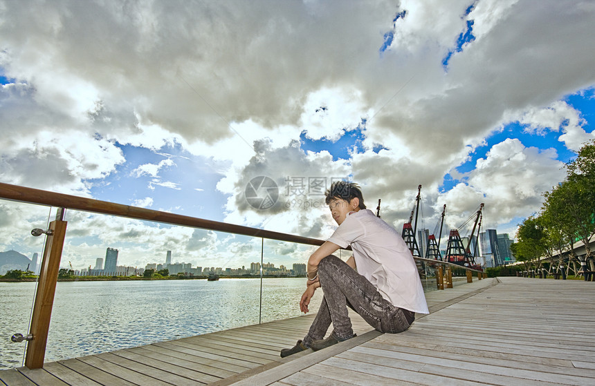 坐在公园里的亚洲人牛仔裤码头蓝色孤独放松市中心旅游海洋日落旅行图片