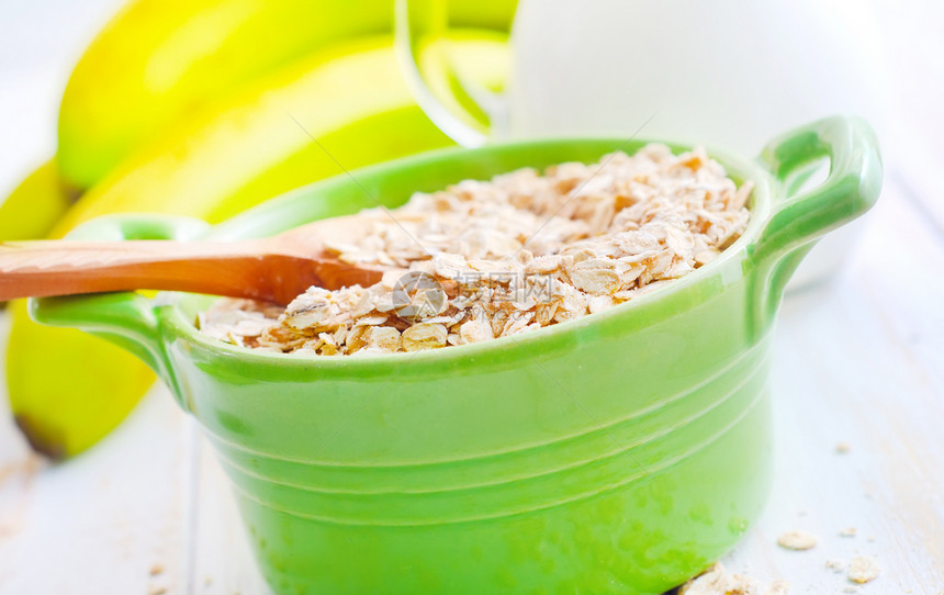 绿碗中含香蕉和牛奶的煤炭片片饮食麦片代谢食物葡萄干薄片玉米木头勺子谷物图片