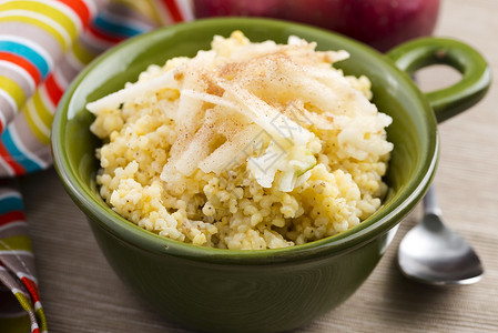 加苹果和肉桂的甜小米粥片黄色粮食谷物稀饭早餐勺子玻璃煮沸服务南瓜背景图片