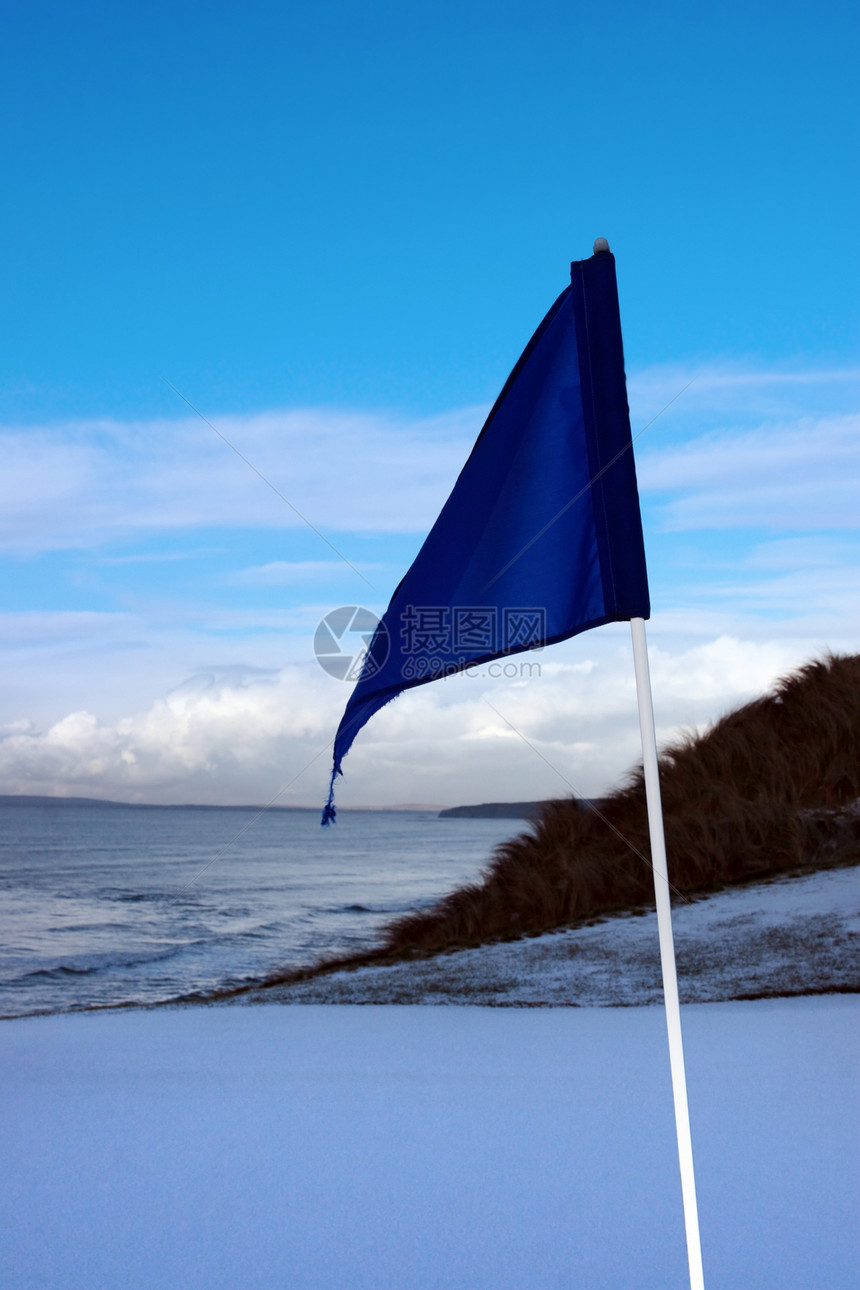 冬季绿绿色高尔夫球场和一面蓝色闪亮的旗帜图片