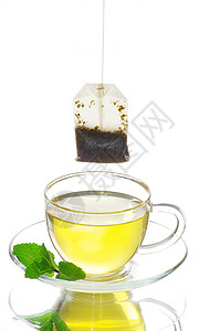 茶杯中的茶绿色玻璃树叶白色杯子液体一杯茶概念柠檬背景图片
