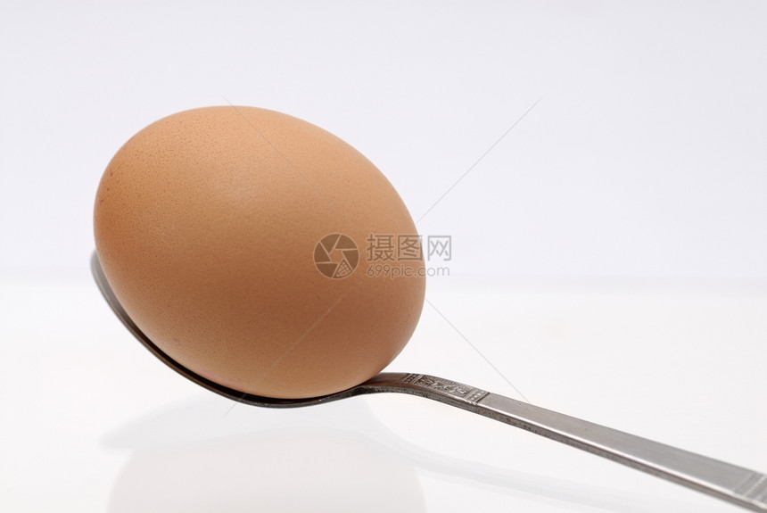 一个鸡蛋在茶匙上 白色背景图片