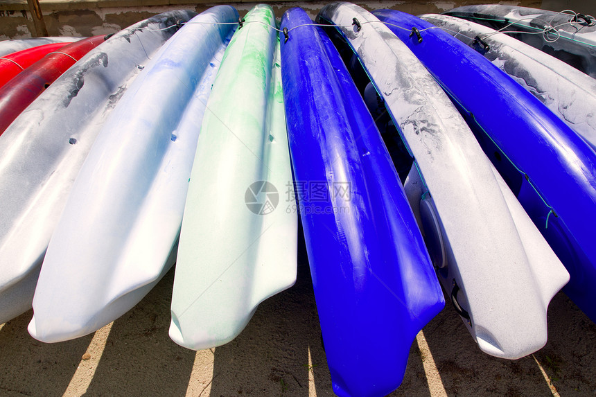 在阳光明媚的白天躺在沙滩上的海滩彩色皮艇排爱好血管独木舟海洋支撑假期塑料晴天探索运输图片