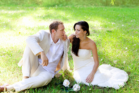 一对夫妇刚刚结婚 坐在公园草地上玫瑰女士婚姻花朵成人男性裙子阳光男人恋人仪式高清图片素材