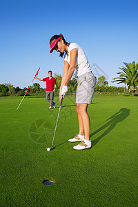妇女高尔夫球员绿色打洞高尔夫球夫妻玩家锻炼法庭晴天推杆享受女性游戏娱乐帽高清图片素材