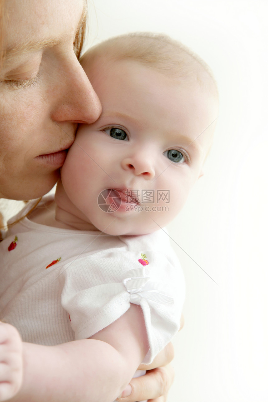 微笑着亲吻小婴儿的母亲儿子新生女儿生活孩子幸福皮肤家庭金发妈妈图片