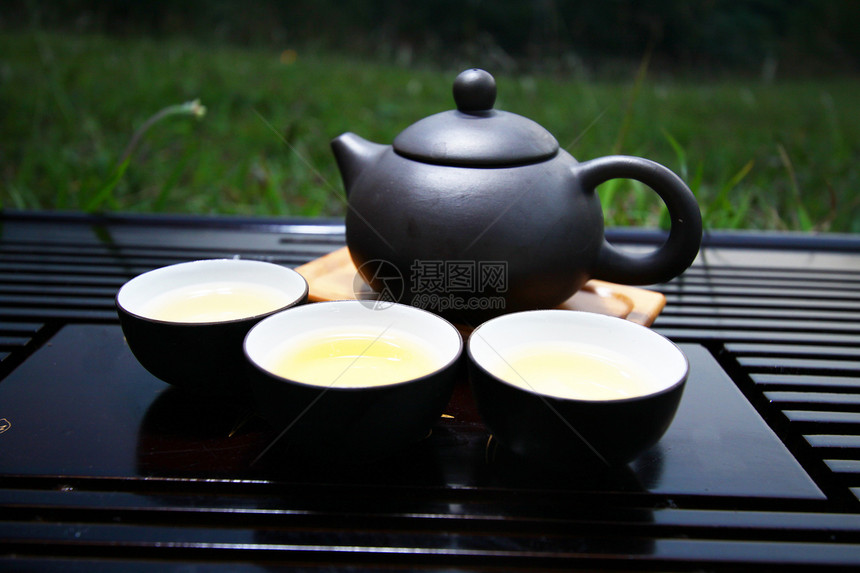 在草地上泡中国茶茶壶杯子草本植物竹子制品黏土情调叶子生活饮料图片