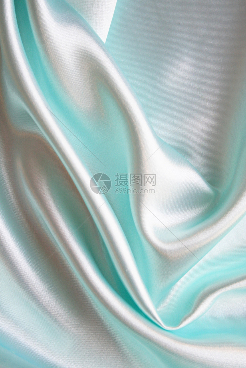 平滑优雅的蓝色丝绸作为背景生产材料版税投标曲线海浪银色布料折痕织物图片