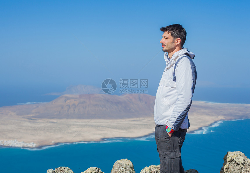 人类站在悬崖边缘的景象海洋自由旅行石头背包游客岩石成就公园运动图片