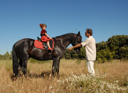 骑马的儿童父亲训练宠物黑色运动男性学习蓝色天空孩子背景图片