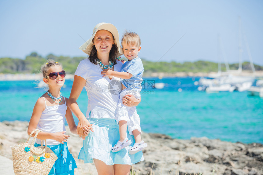 三口三口家庭在热带海滩上行走女士女性太阳镜异国母亲女孩海洋海岸线喜悦乐趣图片
