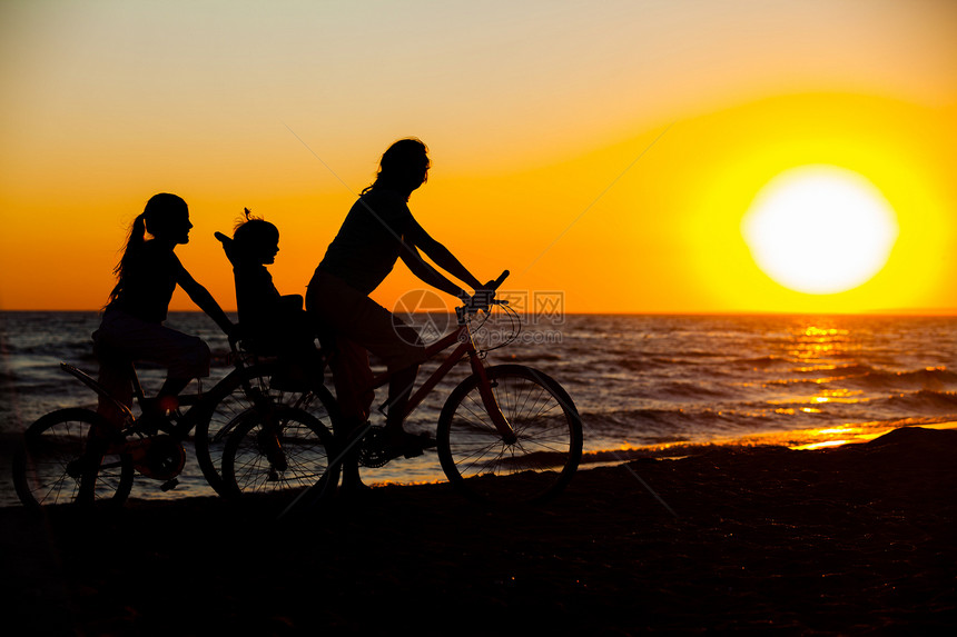 骑自行车的妈妈和孩子 在车轮上女性自由女孩家庭天空乐趣快乐海滨母亲日落图片