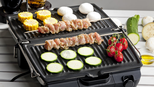 电烤炉上的肉片和蔬菜美食玉米营养盘子静物烧烤食物电烤箱西红柿炊具背景图片